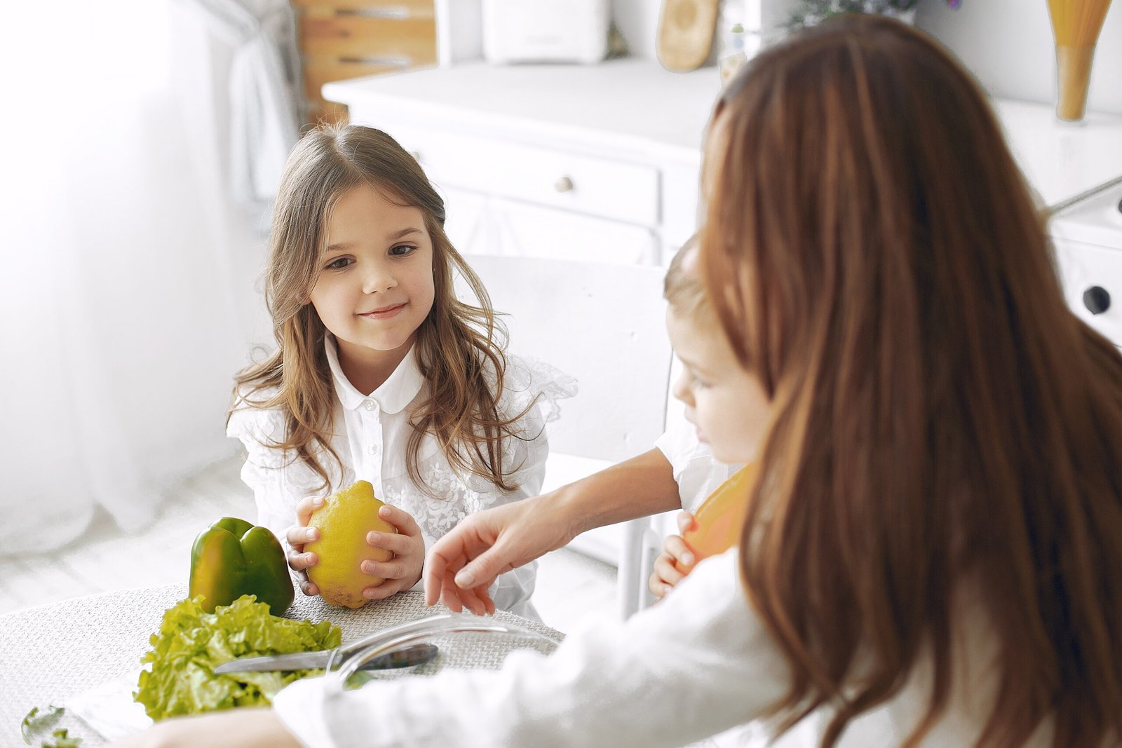 Family in a kitchen. Beautiful mother with children. Lady in white blouse.